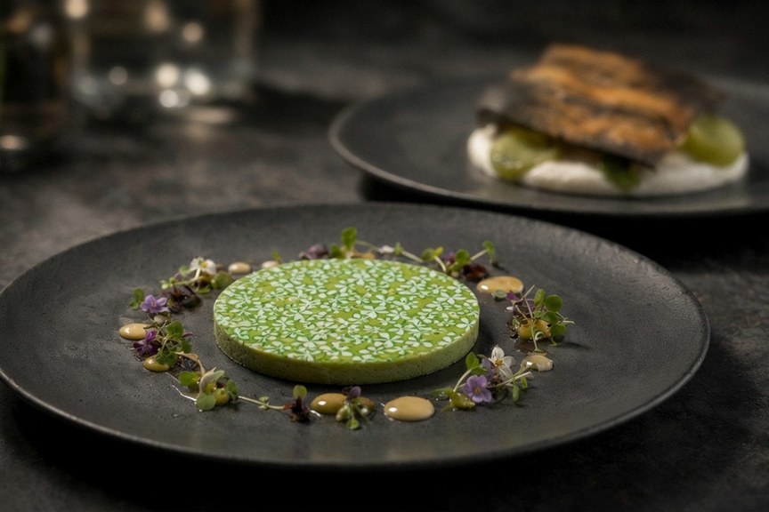 Illustrative AI food photo: a bright green round course on a black plate
